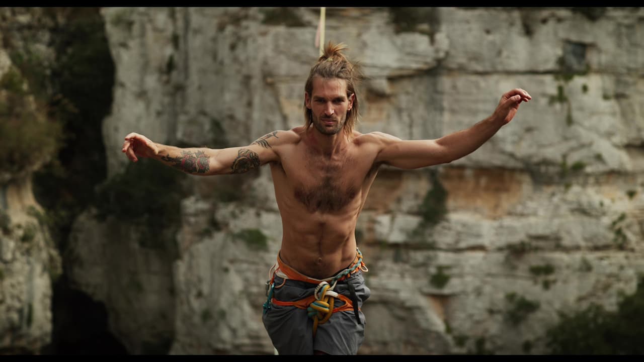 Inquadratura cinematografica di Alessandro in equilibrio davanti a una parete di roccia
