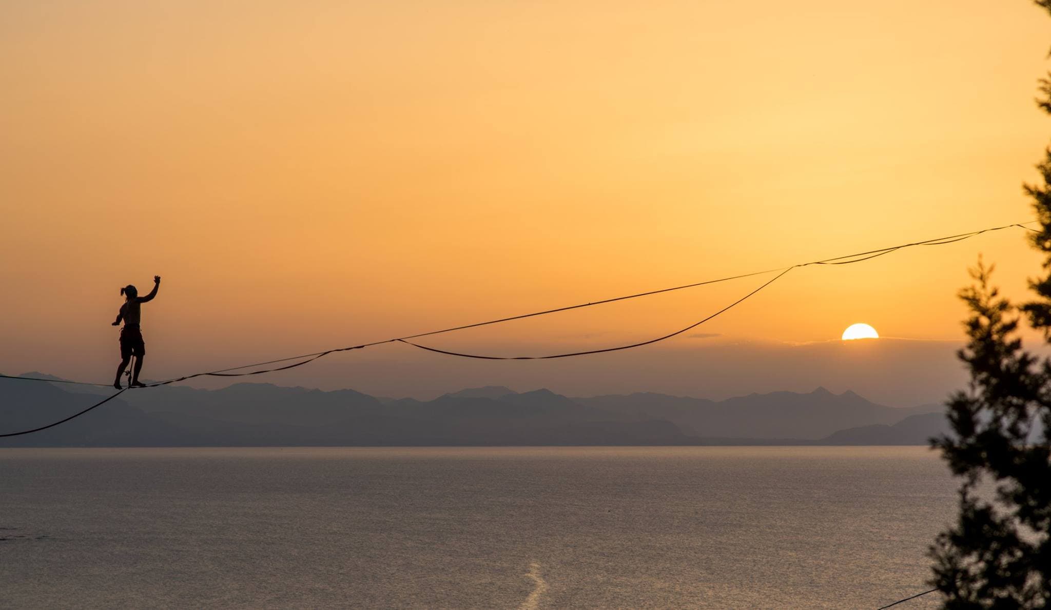 Alessandro in equilibrio su una linea al tramonto, con il mare sullo sfondo